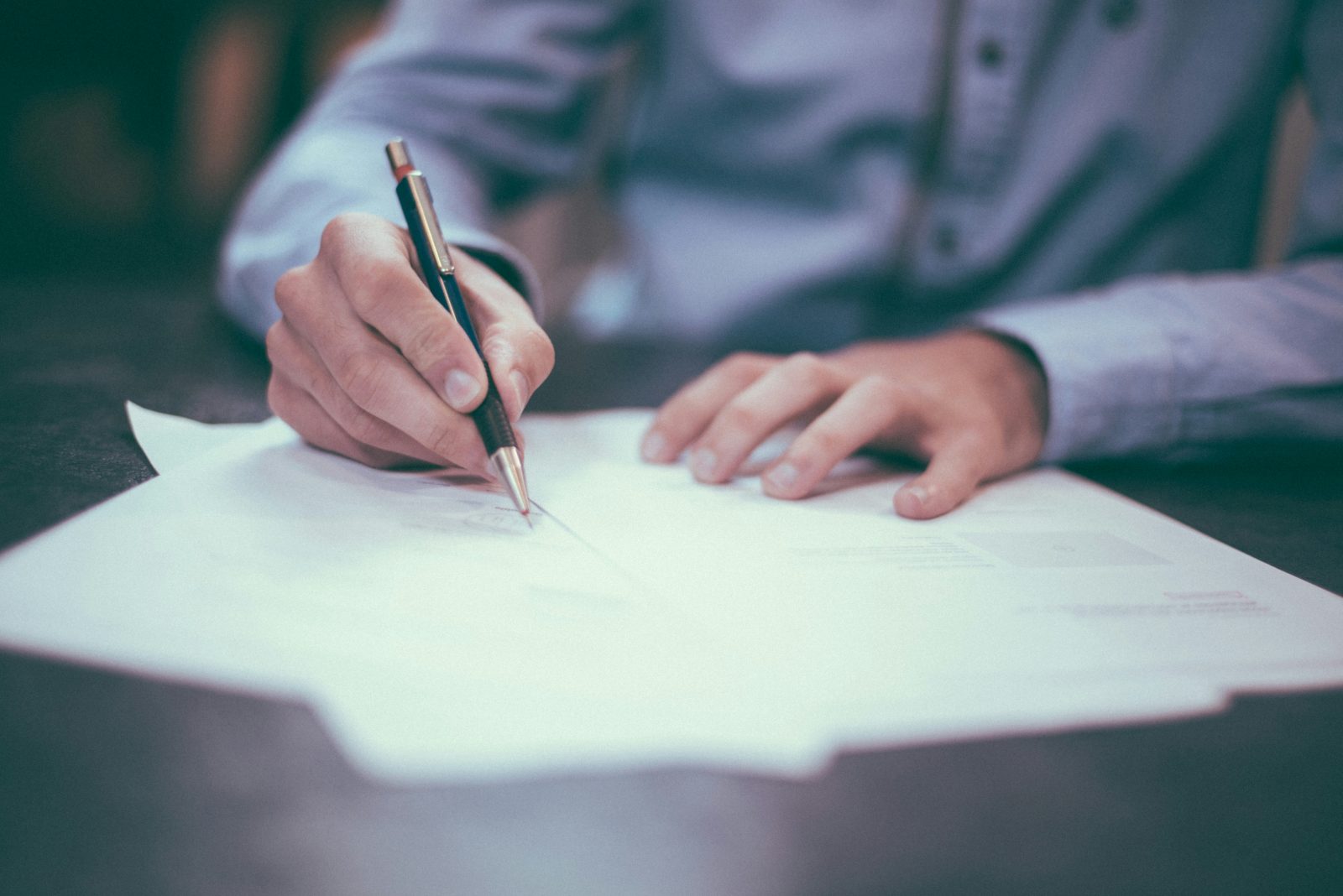 Person signing compliance documents at a desk